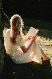 a person sitting on the ground reading a book