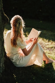 a person sitting on the ground reading a book