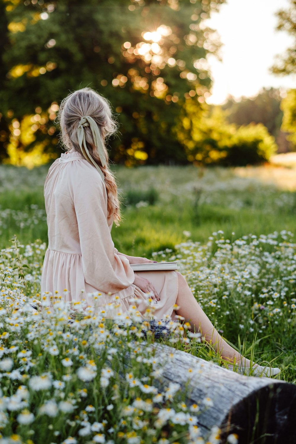 a woman sitting in a field of flowers