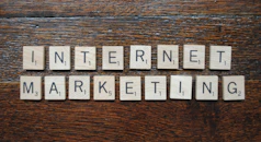 Wooden Scrabble tiles spell out the words 'INTERNET MARKETING' on a textured wooden surface.