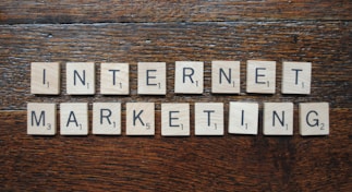 Wooden Scrabble tiles spell out the words 'INTERNET MARKETING' on a textured wooden surface.