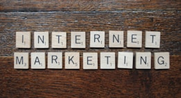 Wooden Scrabble tiles spell out the words 'INTERNET MARKETING' on a textured wooden surface.