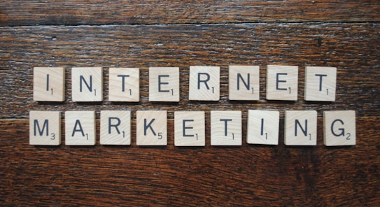 Wooden Scrabble tiles spell out the words 'INTERNET MARKETING' on a textured wooden surface.