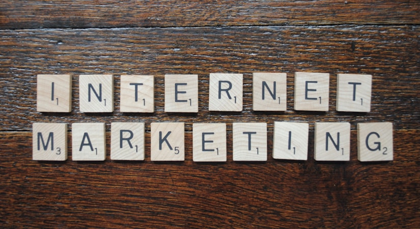 Wooden Scrabble tiles spell out the words 'INTERNET MARKETING' on a textured wooden surface.