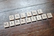 Scrabble tiles arranged to spell 'ONLINE MARKETING' on a wooden table with a textured surface.