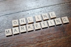 Scrabble tiles arranged to spell 'ONLINE MARKETING' on a wooden table with a textured surface.