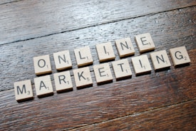 Scrabble tiles arranged to spell 'ONLINE MARKETING' on a wooden table with a textured surface.