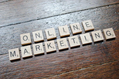 Scrabble tiles arranged to spell 'ONLINE MARKETING' on a wooden table with a textured surface.