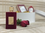 Close-up of rose amber attar bottle beside delicate beige silk fabric and soft candlelight.