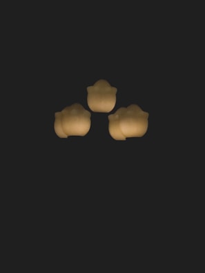 Three glowing shapes arranged in a triangular formation against a dark background.