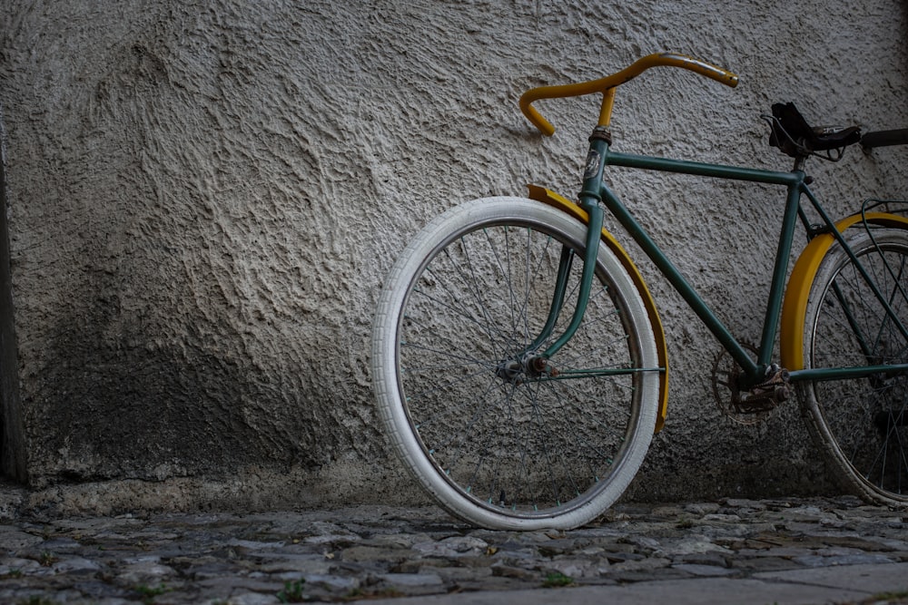 a green bicycle parked next to a wall