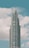 A modern, tall skyscraper with a series of tiered sections rising against a backdrop of a blue sky with scattered white clouds.