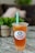 A plastic cup filled with iced tea or boba tea labeled 'Happy Boba' with a green straw. The drink has a lemon slice and appears to have boba or jelly pieces at the bottom. It is placed on a marble or granite surface with a blurred background featuring greenery and soft furnishings.