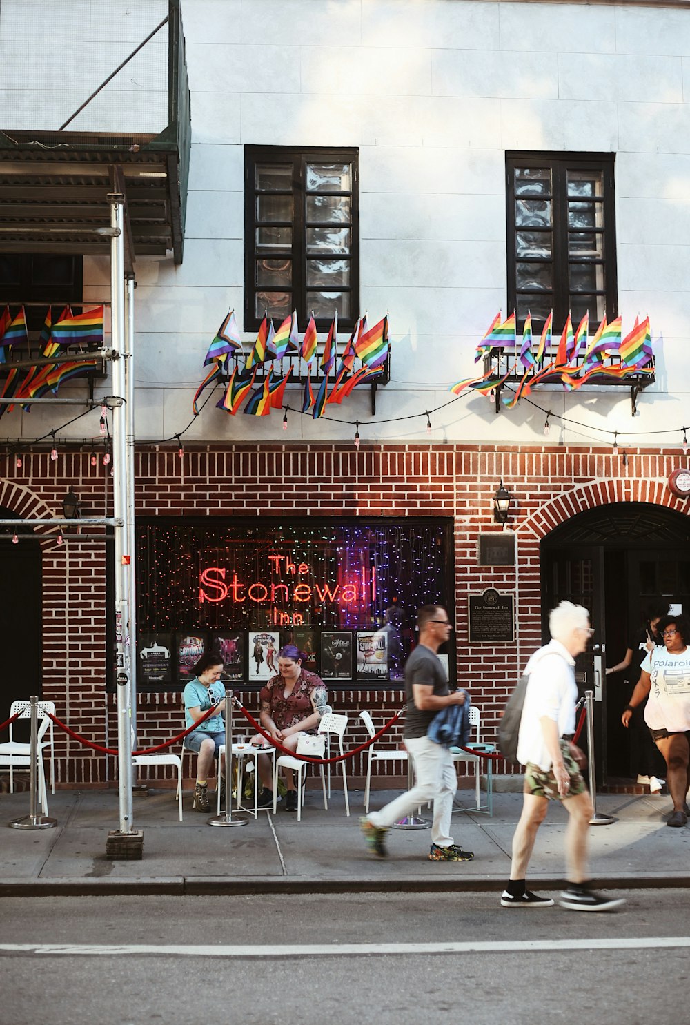 a group of people walking on a sidewalk in front of a restaurant