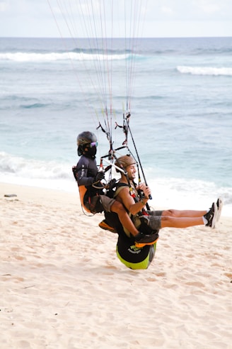 a couple of people parasailing on a beach
