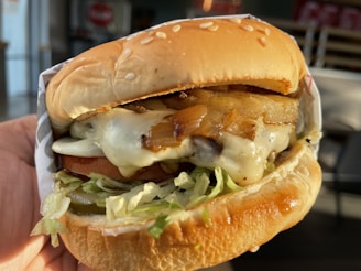A close-up of a special burger topped with caramelized onions and melted cheese dripping.