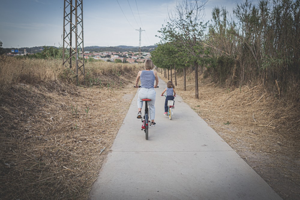 two people riding bikes on a path