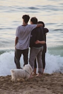 a couple of people kissing on a beach with a dog