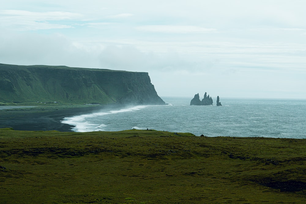 a grassy area next to a body of water with a hill in the background