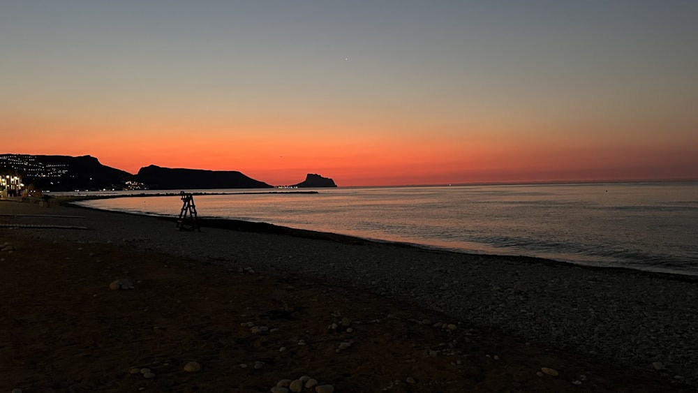 a beach with a body of water and a sunset