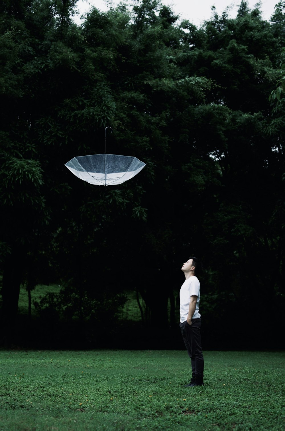 a man standing in a grassy area looking at a large white object