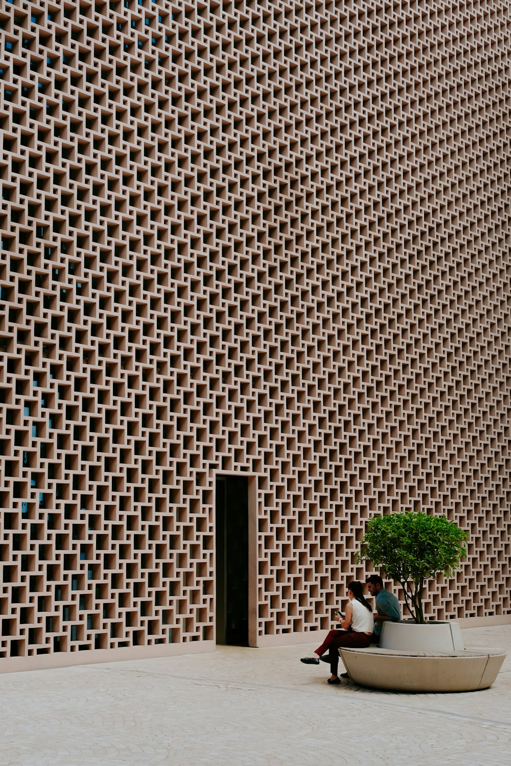 a man and woman sitting on a bench in front of a wall