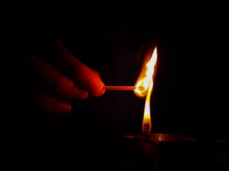 a hand holding a lit candle