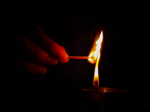 a hand holding a lit candle