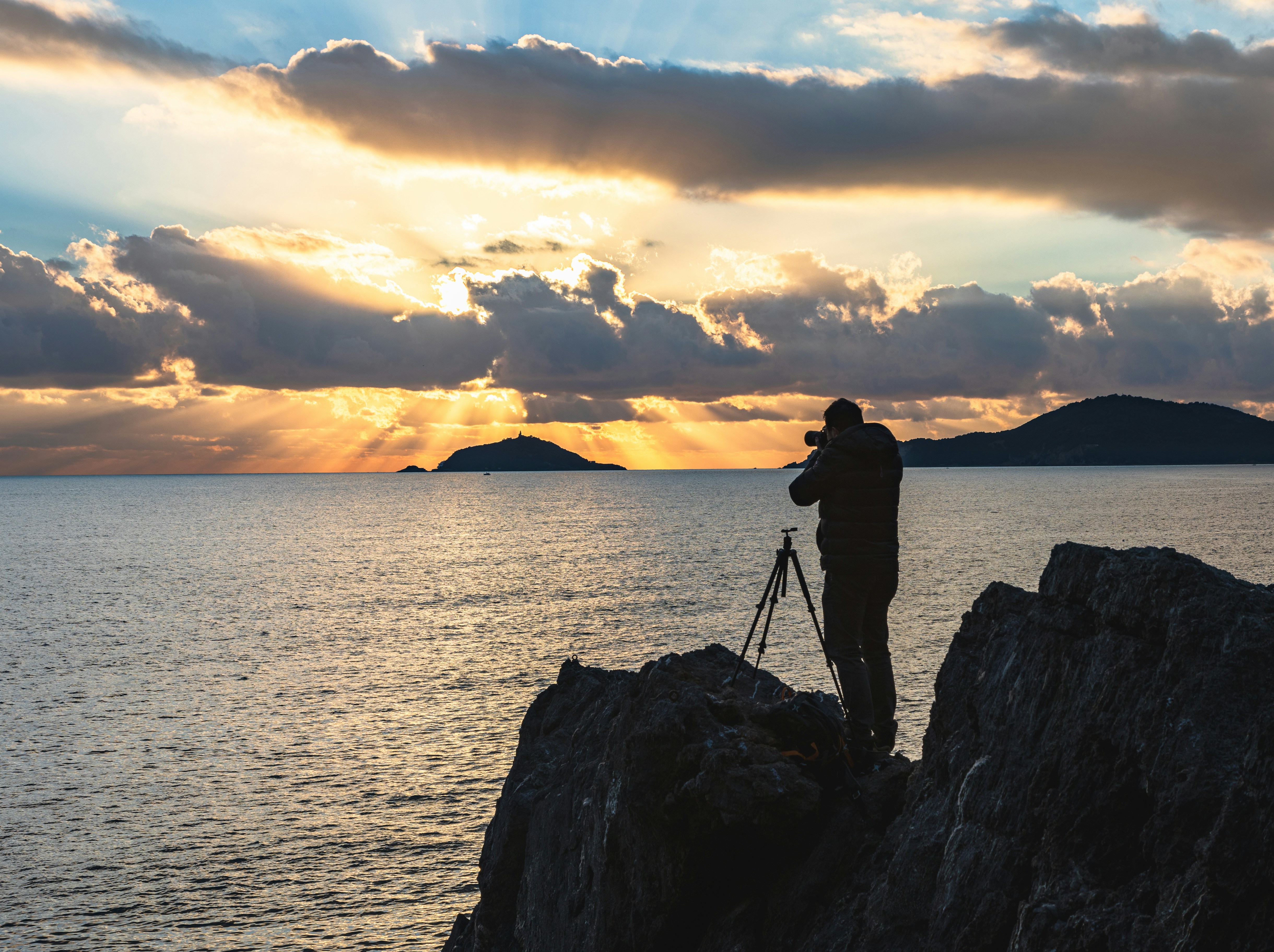 a man standing on a rock looking at the sunset