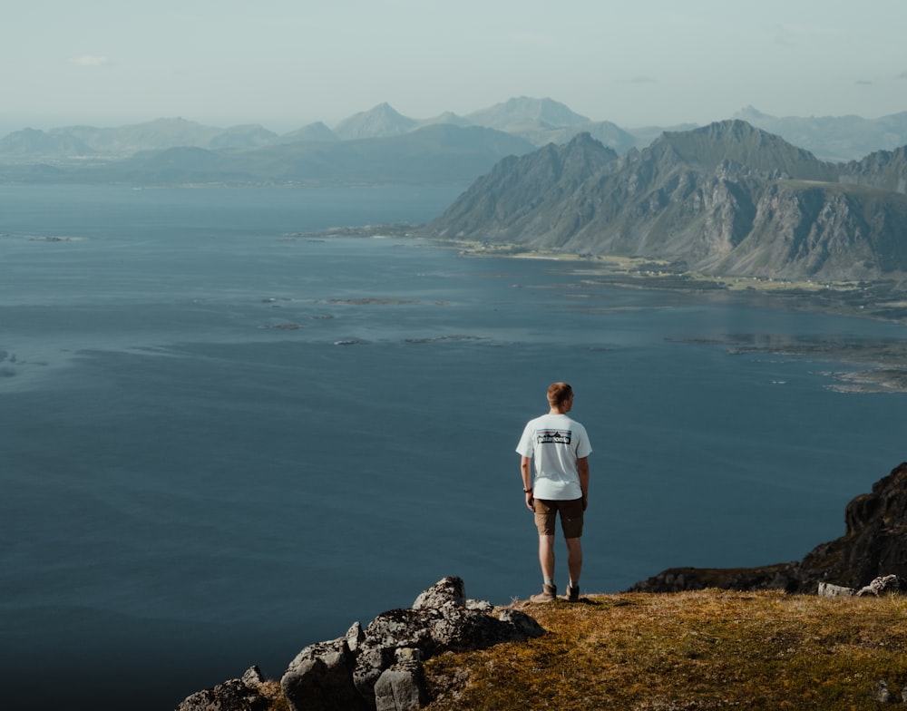 a man standing on a cliff overlooking a body of water