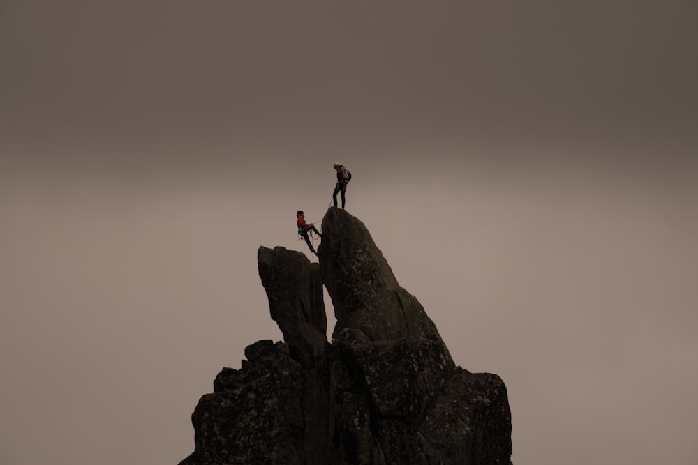 a couple of people climbing a rock