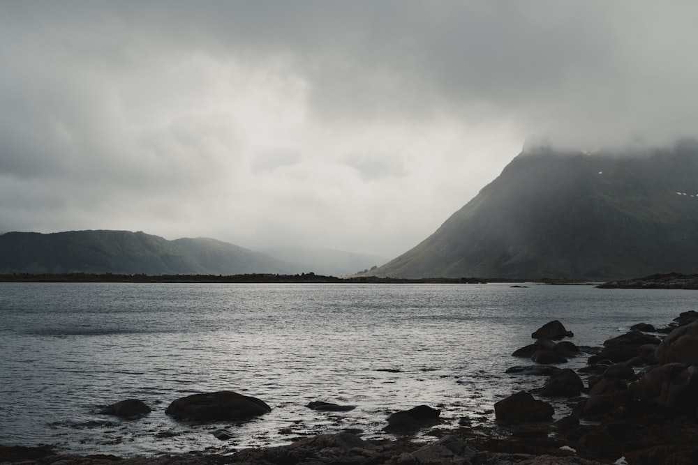 a rocky beach with a large mountain in the background