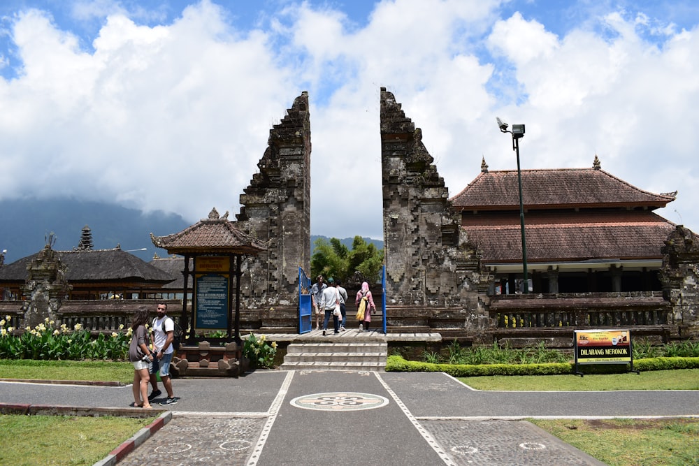 a group of people walking on a road next to a stone building