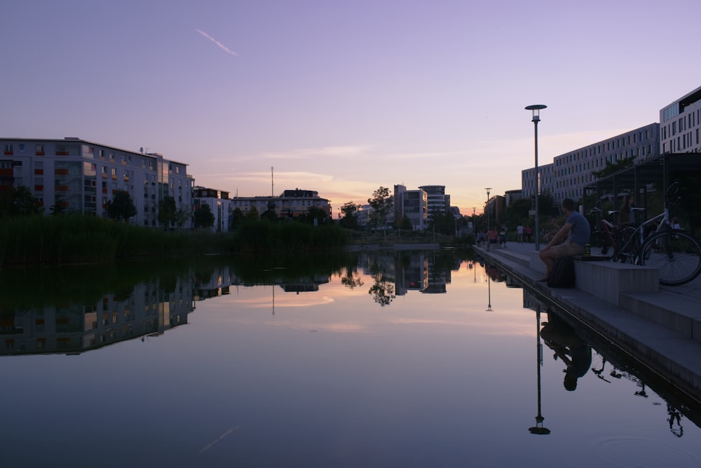 a person sitting on a bench next to a body of water