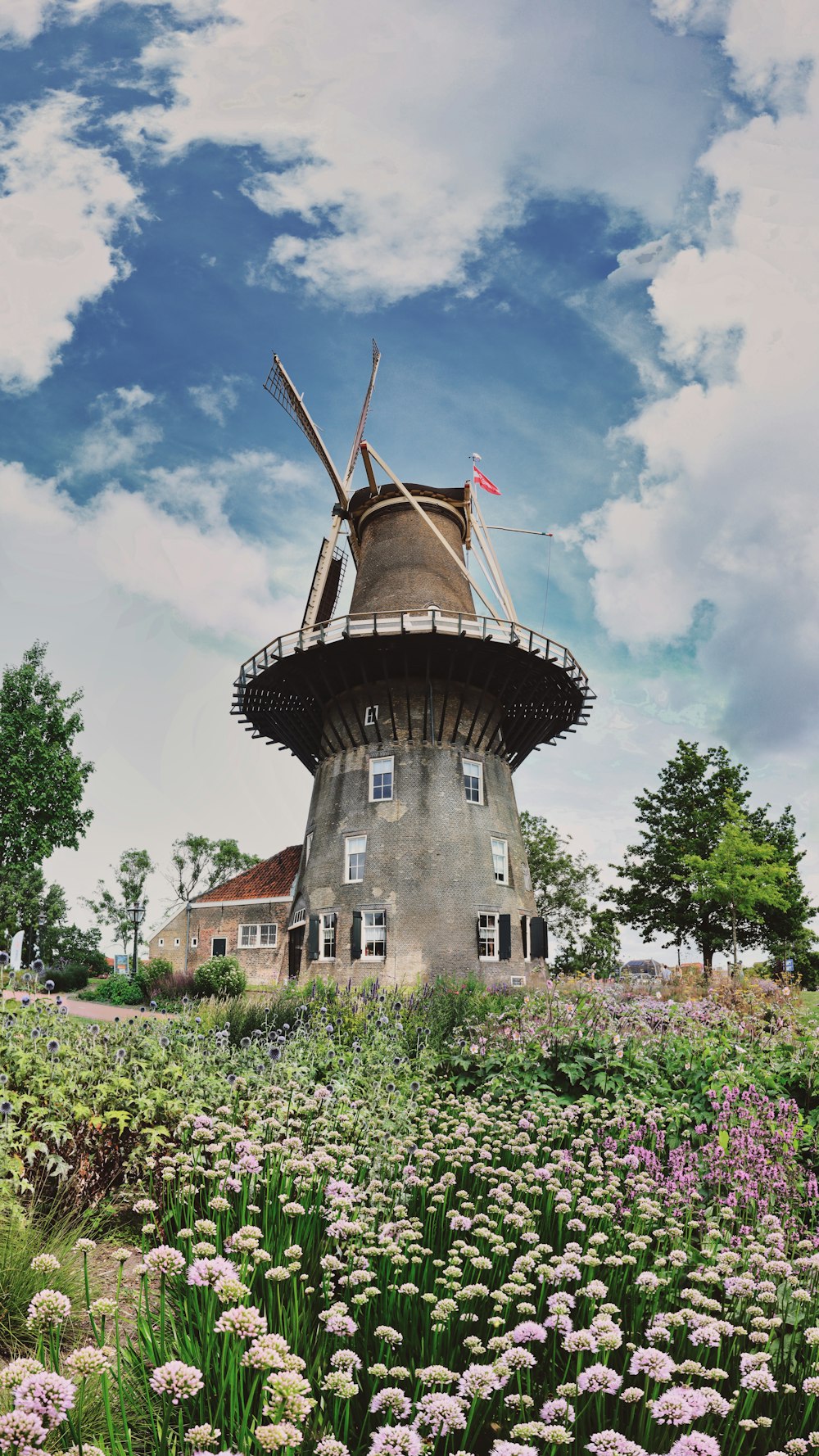 a building with a tower and flowers in front of it