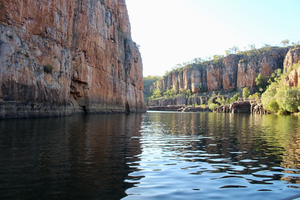 a body of water with cliffs and trees on the side with Nitmiluk National Park in the background