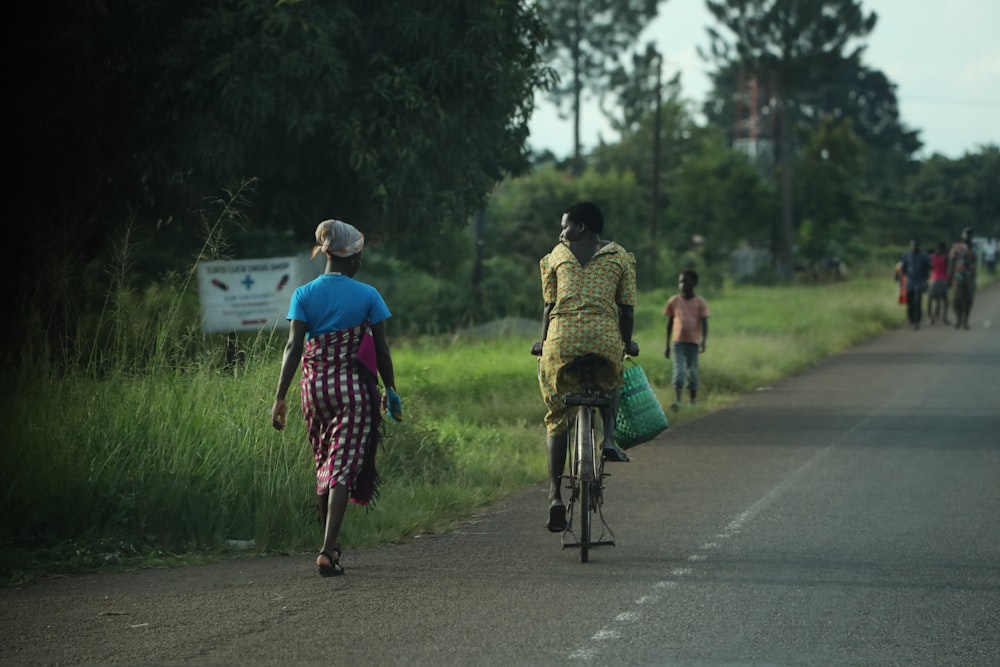 a person riding a bicycle with a child on the back