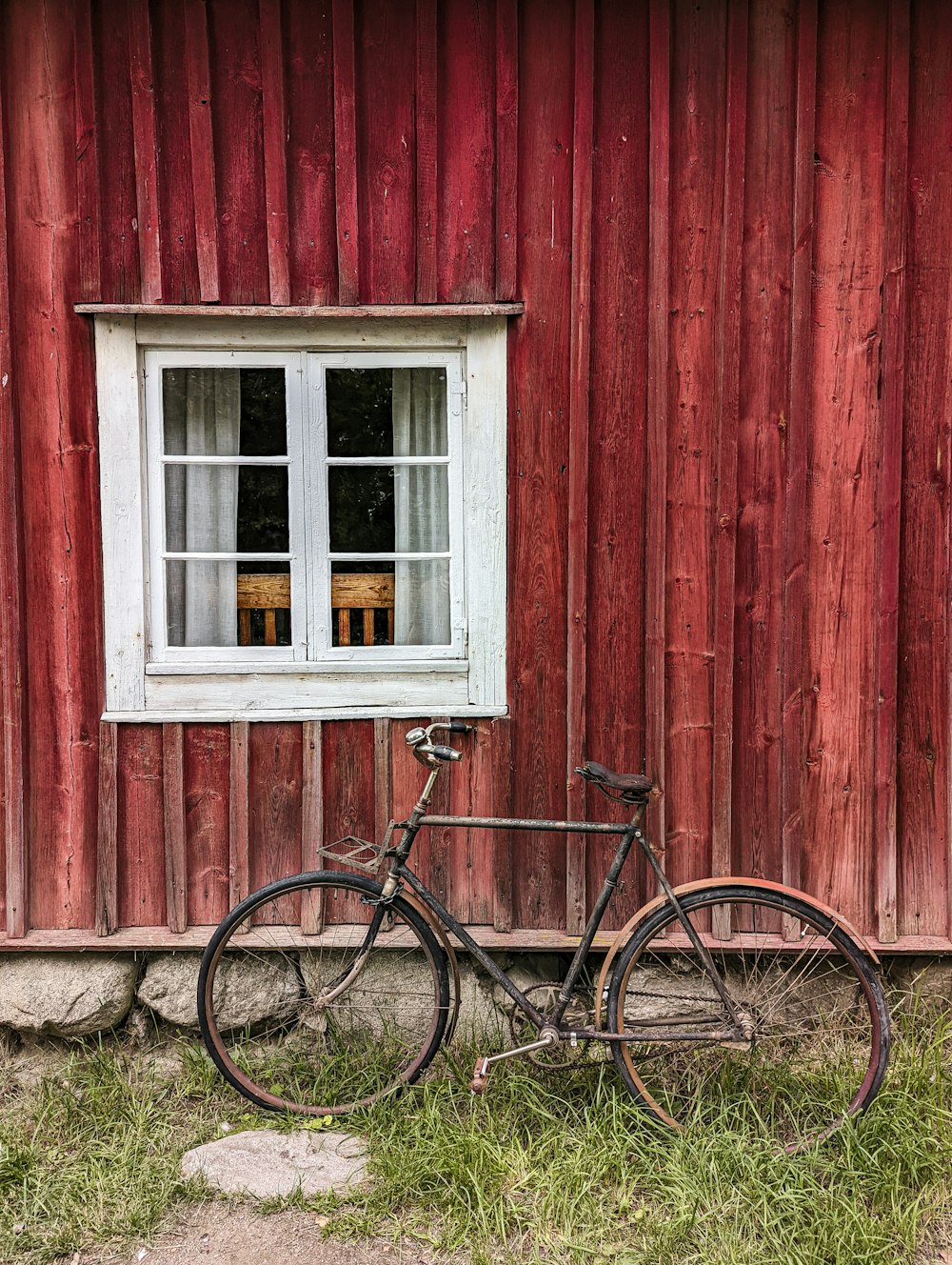 a bicycle parked in front of a red barn