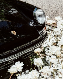 a black car parked in a lot of white flowers