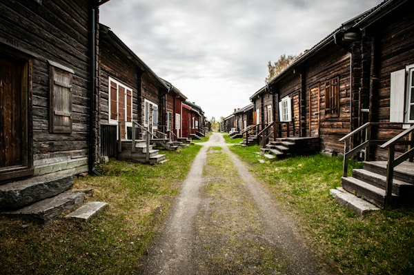 A dirt road between two wooden buildings — Swedish Lapland, Sweden