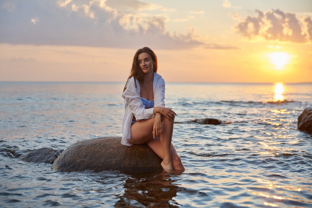 Eine Person, die auf einem Felsen im Wasser sitzt