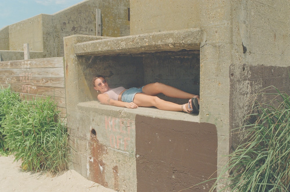a boy lying in a hole in a stone wall