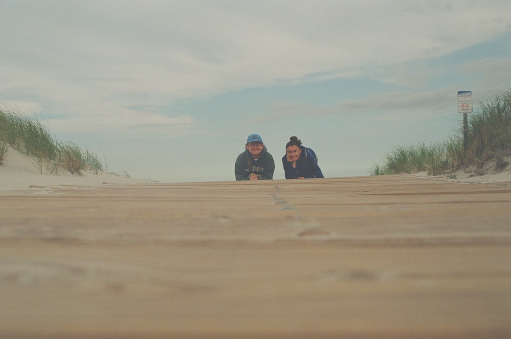 two people sitting on a sandy beach