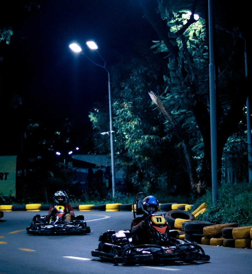 a group of people racing go karts on a road at night