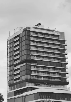 A sleek modern building under construction, framed by a charcoal sky with golden light accents highlighting architectural details.