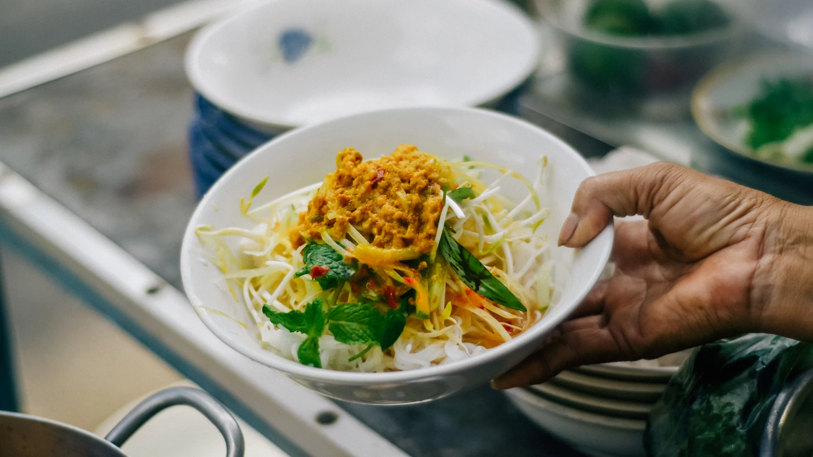 A person holds a bowl of food outdoors.