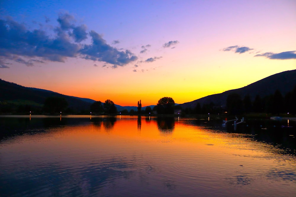 a body of water with trees and hills in the background