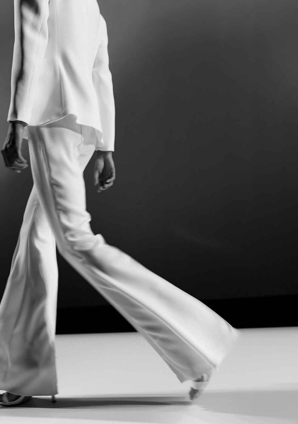 Close view of fluid white tailoring moving across a dark runway