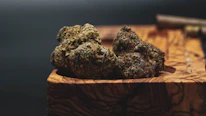 Close-up of vibrant cannabis buds resting on natural wooden surface.
