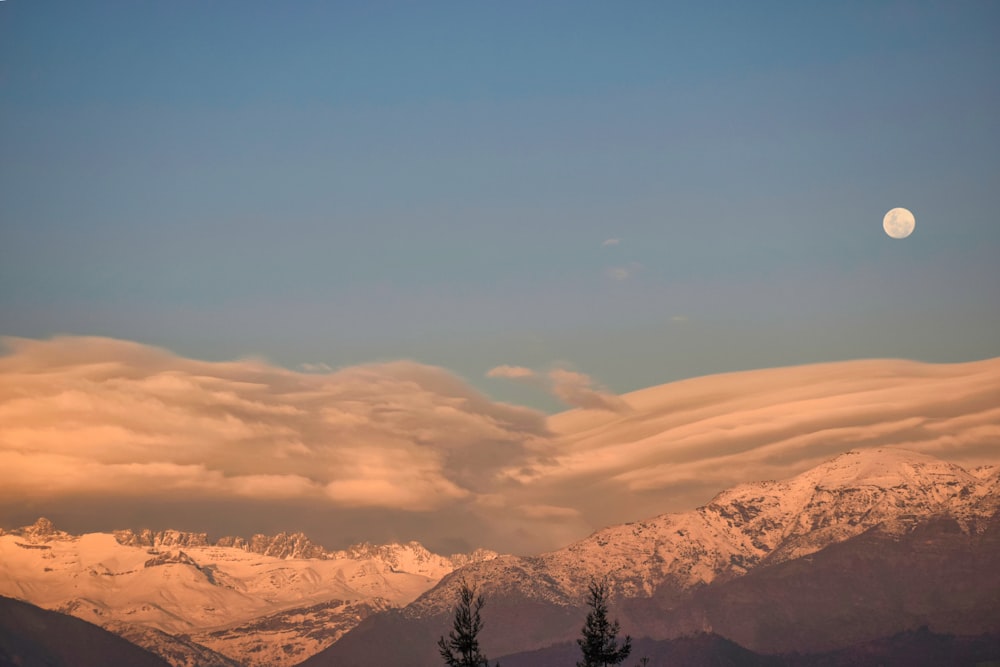 a moon in the sky over mountains